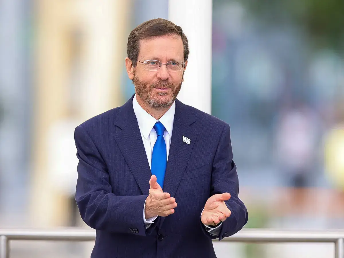O presidente Isaac Herzog fazendo um gesto com a mão durante um evento.