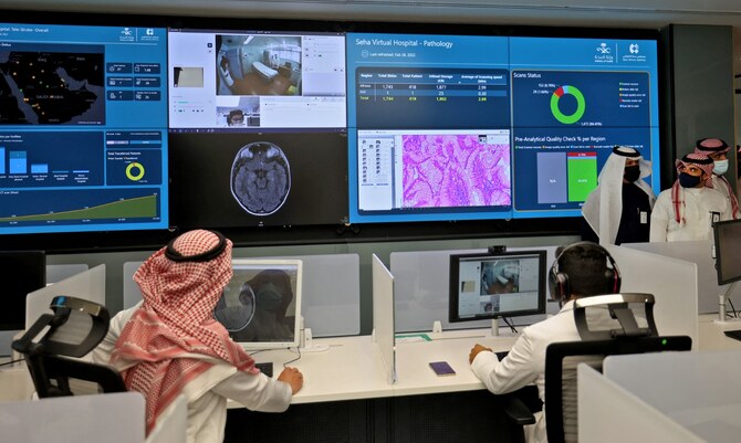 Dois árabes sentados em frente ao computador, com imagens na tela, incluindo uma do cérebro, destacando o impacto da telemedicina na saúde da Arábia Saudita.
