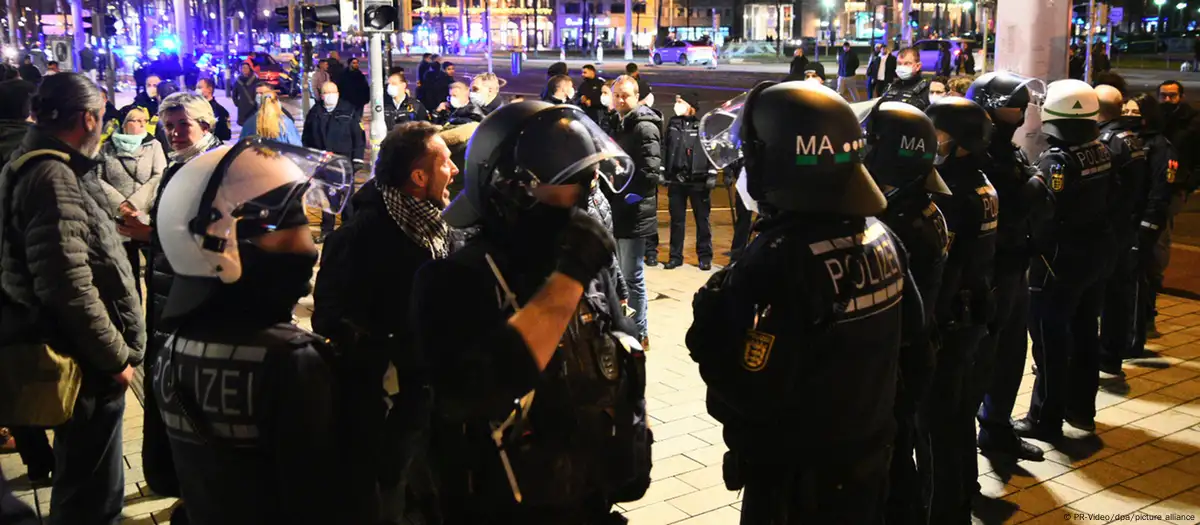 Manifestantes e policiais em confronto, representando o aumento da violência e do terrorismo na Alemanha.