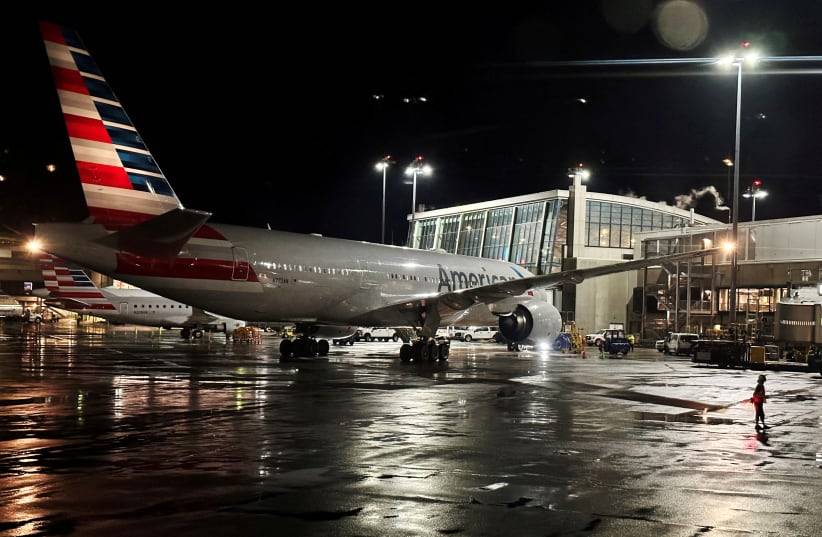 Avião da American Airlines parado no portão de um aeroporto à noite, destacando a suspensão dos voos durante a véspera de Natal.
