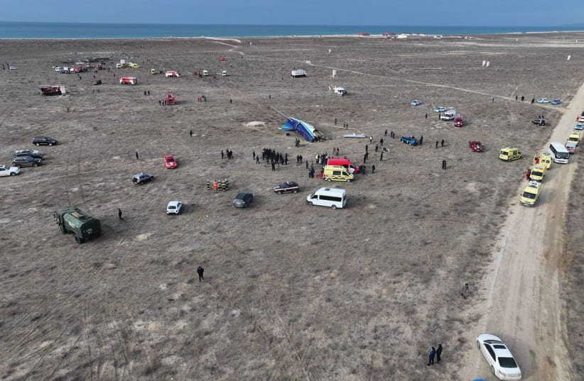 Destroços do avião no chão, com ambulâncias, carros e pessoas, possivelmente da polícia, no local do acidente no Cazaquistão