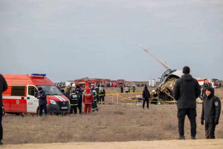 Destroços do avião da Azerbaijan Airlines no chão, com policiais e ambulâncias no local do acidente.