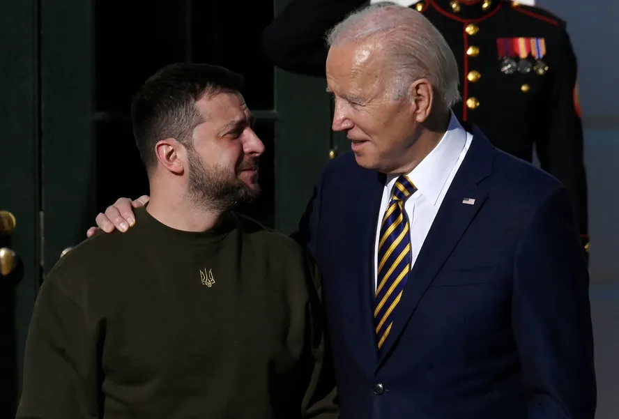 Biden e o presidente ucraniano sorrindo juntos, com Biden colocando a mão ao redor do presidente da Ucrânia, durante a revelação da última rodada de assistência militar dos EUA.