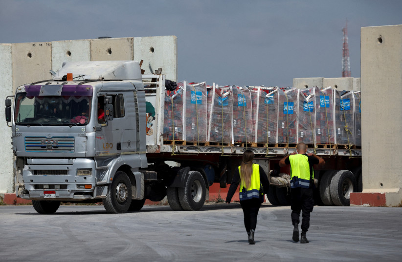 Caminhão transportando ajuda humanitária em Gaza, com um homem e uma mulher, provavelmente trabalhadores humanitários, ao lado.