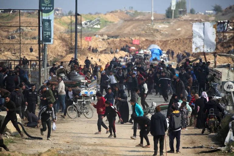 Palestinos deslocados correm para se proteger após tiros de advertência disparados pelo exército israelense, enquanto se dirigem ao Corredor Netzarim, vindo do sul da Faixa de Gaza. [Eyad Baba/AFP]