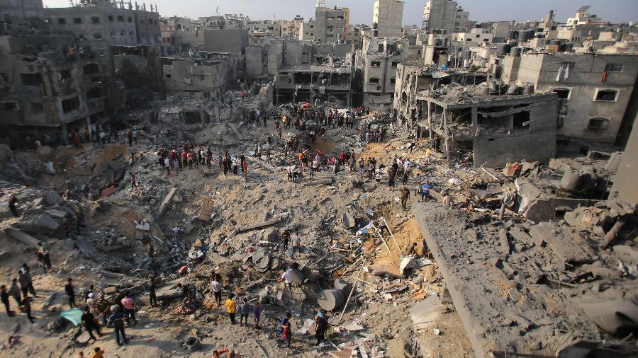 Destruição em Gaza com moradores ao redor, refletindo os impactos do conflito entre Israel e Hamas.