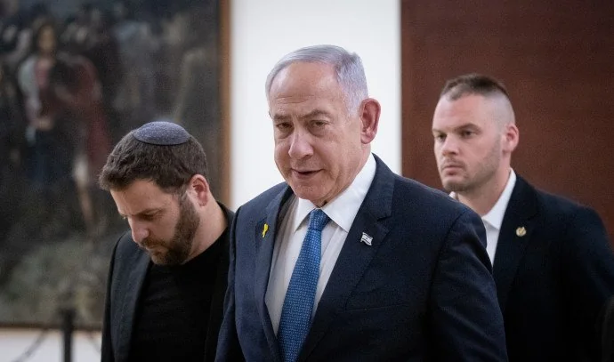 Benjamin Netanyahu andando, acompanhado por dois homens.