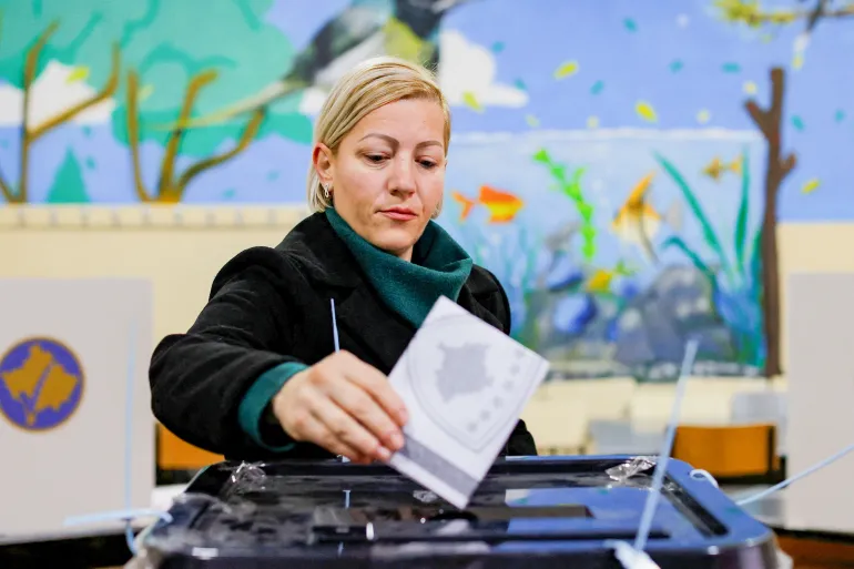 Uma mulher vota durante as eleições parlamentares em North Mitrovica, Kosovo [Valdrin Xhemaj/Reuters].