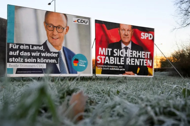 Cartazes de campanha eleitoral para Friedrich Merz da União Democrata Cristã (CDU) e para o chanceler alemão Olaf Scholz do Partido Social-Democrata da Alemanha (SPD) em Colônia, Alemanha, em 2 de fevereiro de 2025 [Jana Rodenbusch/Reuters]. Fonte: Al Jazeera