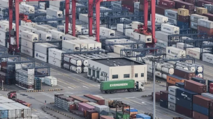 Um caminhão de carga circula entre contêineres empilhados no Porto de Yangshan, em Xangai, China, em 29 de março de 2018 [AP]. Fonte: Al Jazeera