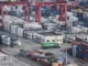 Um caminhão de carga circula entre contêineres empilhados no Porto de Yangshan, em Xangai, China, em 29 de março de 2018 [AP]. Fonte: Al Jazeera