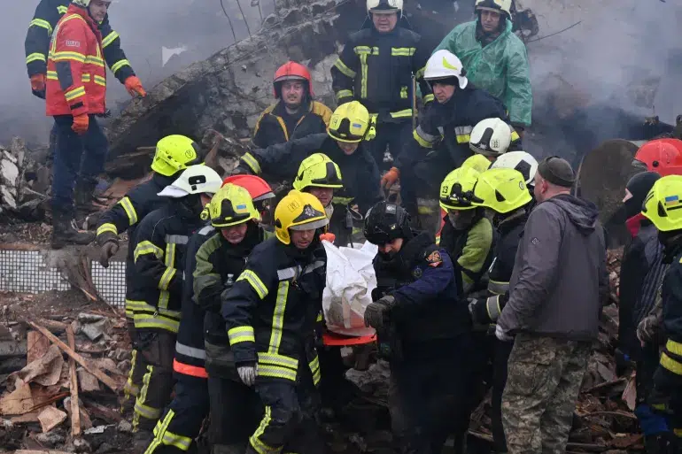 Bombeiros carregam o corpo de um civil após um ataque de míssil em Poltava [Sergey Bobok/AFP]