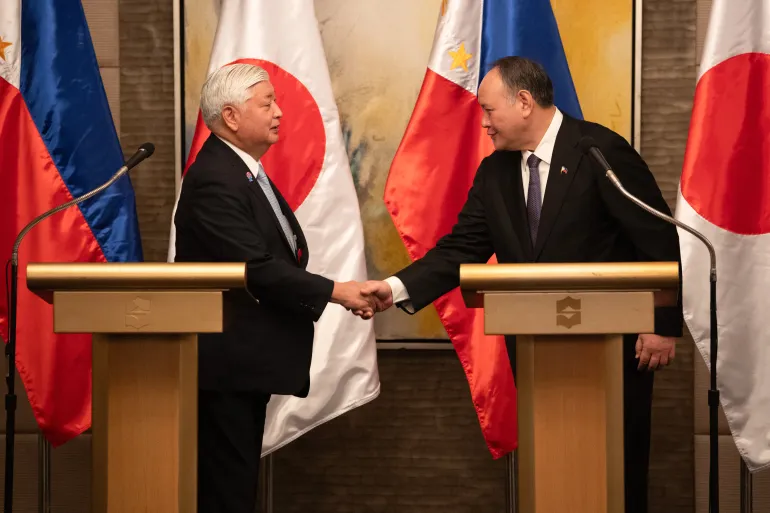 O Secretário de Defesa das Filipinas, Gilberto Teodoro, aperta a mão do Ministro da Defesa do Japão, Gen Nakatani, após uma coletiva de imprensa conjunta em Manila, em 24 de fevereiro de 2025. [Ted Aljibe/AFP] Fonte: Al Jazeera