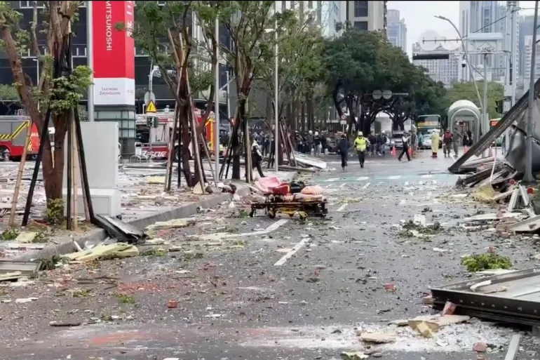 Esta imagem, retirada de um vídeo da TVBS de Taiwan, mostra destroços espalhados pelas ruas após uma explosão na loja de departamentos Shin Kong Mitsukoshi na cidade de Taichung [TVBS via AP]. Fonte: AL Jazeera