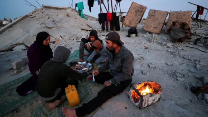 Uma família palestina quebra o jejum do Ramadã sobre os escombros de sua casa no campo de refugiados de Jabalia, no norte de Gaza, 2 de março de 2025 [Mahmoud Issa/Reuters]. Fonte: Al Jazeera