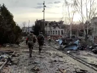 Membros das forças russas caminham pasto de um prédio destruído na cidade de Sudzha, que foi recentemente retomada pelas forças armadas da Rússia durante o conflito Rússia-Ucrânia na região de Kursk, Rússia