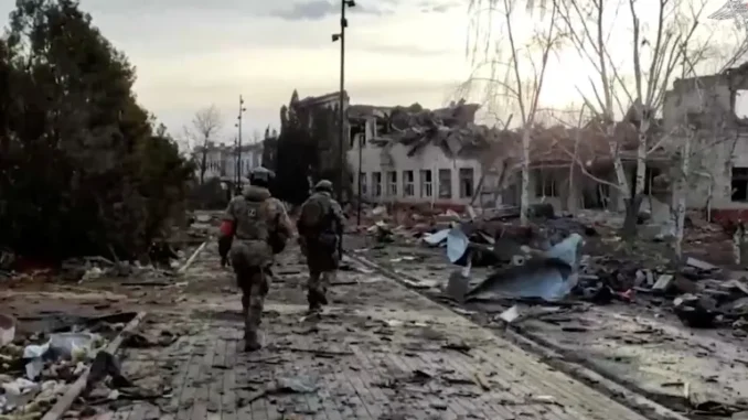2025-03-15T125223Z_1640329604_RC2ODDAW4EL6_RTRMADP_3_UKRAINE-CRISIS-RUSSIA-KURSK-1742058890 Membros das forças russas caminham pasto de um prédio destruído na cidade de Sudzha, que foi recentemente retomada pelas forças armadas da Rússia durante o conflito Rússia-Ucrânia na região de Kursk, Rússia