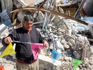 Um homem pendura bandeiras do Ramadã na Cidade de Gaza enquanto a primeira fase de um cessar-fogo entre Israel e Hamas expira em 1º de março de 2025.[Omar al-Qattaa/AFP] Fonte: Al Jazeera
