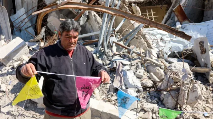 Um homem pendura bandeiras do Ramadã na Cidade de Gaza enquanto a primeira fase de um cessar-fogo entre Israel e Hamas expira em 1º de março de 2025.[Omar al-Qattaa/AFP] Fonte: Al Jazeera