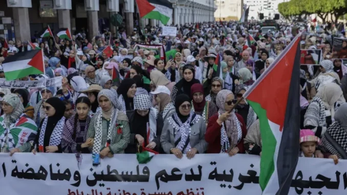 000_39B489D-1743958290 Mulheres erguem um banner durante marcha nacional em apoio aos palestinos e contra a normalização de relações de Marrocos com Israel, na capital Rabat, em 6 de abril de 2025. Foto: Abdel Majid Bziouat/AFP Fonte: Al Jazeera