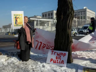 Mulher segura cartaz em protesto contra possível acordo de minerais críticos entre EUA e Ucrânia [Arquivo: Thomas Peter/Reuters] Fonte: Al Jazeera