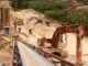 **Alt Text:** Uma visão geral mostra minério de cassiterita e tântalo em uma planta de processamento mineral semi-industrial em Gatumba, no oeste de Ruanda, em 25 de novembro de 2009. **Legenda:** Minérios de cassiterita e tântalo sendo processados em uma planta semi-industrial em Gatumba, oeste de Ruanda, novembro de 2009. **Descrição:** A imagem retrata um processo de extração e beneficiamento de minerais em uma planta semi-industrial em Gatumba, localizada no oeste de Ruanda. O local é conhecido pela produção de cassiterita (um mineral rico em estanho) e tântalo, que são componentes essenciais na fabricação de diversos dispositivos eletrônicos. Esses minerais têm grande importância estratégica para a economia de Ruanda, apesar de estarem frequentemente ligados a questões de exploração e conflitos na região. **Resumo:** Em uma planta de processamento semi-industrial em Gatumba, Ruanda, minérios de cassiterita e tântalo são processados, destacando a relevância dessa atividade na economia local e a controvérsia em torno da mineração de recursos estratégicos na região.