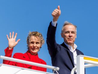 Mark Carney, primeiro-ministro do Canadá, e sua esposa, Diana Fox Carney, acenam ao público durante sua campanha eleitoral no Aeroporto Internacional de Halifax Stanfield, Nova Escócia, 21 de abril de 2025.