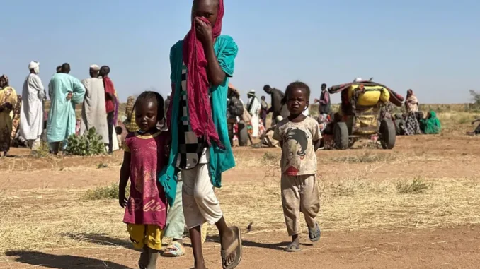 AFP__20250213__36XQ746__v2__HighRes__SudanConflictRefugees-1746093609 Mulher sudanesa deslocada, acompanhada de crianças, caminha em um campo de refugiados perto da cidade de Tawila, em Darfur do Norte, em 11 de fevereiro de 2025, durante a guerra em andamento entre o exército e as forças paramilitares.