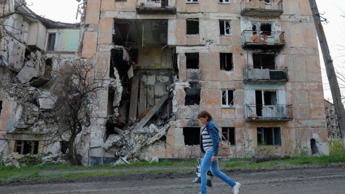 Mulher passa por prédio residencial destruído em Toshkivka, região de Luhansk, controlada pela Rússia, Ucrânia — 17 de abril de 2025.