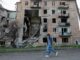 Mulher passa por prédio residencial destruído em Toshkivka, região de Luhansk, controlada pela Rússia, Ucrânia — 17 de abril de 2025.