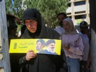 Mulher segura folheto com retratos de líderes do Hezbollah em seção eleitoral em Nabatieh, no sul do Líbano, durante as eleições municipais de maio de 2025.