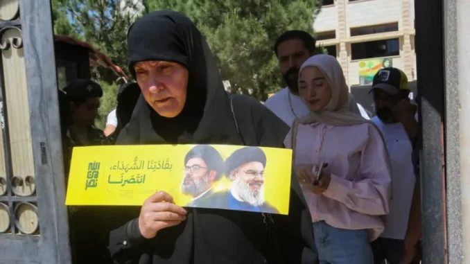 000_47YB2KF-1748088661 Mulher segura folheto com retratos de líderes do Hezbollah em seção eleitoral em Nabatieh, no sul do Líbano, durante as eleições municipais de maio de 2025.