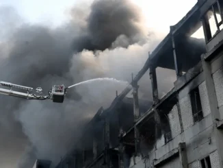 Bombeiro apagando incêndio em planta civil após ataques russos em Kharkiv