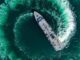 Navio varredor de minas da Marinha da Turquia realiza manobra circular em operação no Mar Negro, visto de cima com trilha de espuma na água.