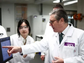 Pesquisadores e executivo em jalecos brancos discutindo dados em um laboratório da UCL.