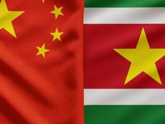 Paisagem diplomática: bandeiras da China e do Suriname lado a lado em frente a uma construção governamental.