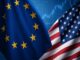 Bandeiras da União Europeia e dos Estados Unidos lado a lado, com gráficos financeiros desfocados ao fundo.