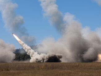 Foguete HIMARS sendo lançado de um campo aberto durante exercício militar, com grande quantidade de fumaça e chama visíveis na base do foguete.