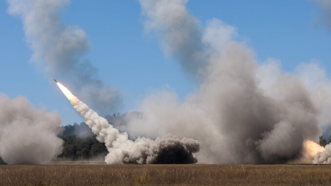 Austrália realiza lançamento inaugural do foguete HIMARS em exercício militar conjunto com os EUA, fortalecendo a segurança no Indo-Pacífico Foguete HIMARS sendo lançado de um campo aberto durante exercício militar, com grande quantidade de fumaça e chama visíveis na base do foguete.