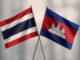 Bandeiras da Tailândia e do Camboja cruzadas em fundo neutro, simbolizando a cooperação e o acordo de paz entre os dois países.