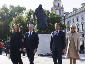 Keir Starmer e sua esposa ao lado de Emmanuel Macron e Brigitte Macron caminhando próximos à estátua de Winston Churchill em Londres, em um dia ensolarado.