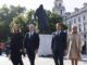 Keir Starmer e sua esposa ao lado de Emmanuel Macron e Brigitte Macron caminhando próximos à estátua de Winston Churchill em Londres, em um dia ensolarado.