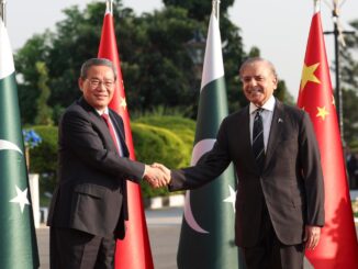 Li Qiang aperta a mão de Shehbaz Sharif diante das bandeiras da China e do Paquistão durante encontro diplomático em 2024