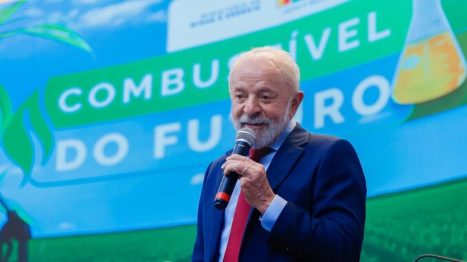 GuUICHlXQAAfr1N Presidente Lula discursa com microfone em evento sobre políticas energéticas, diante de painel com os dizeres "Combustível do Futuro".