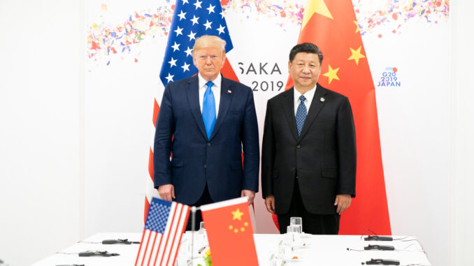 President_Trump_at_the_G20_(48162296741) Donald Trump e Xi Jinping posam lado a lado em frente às bandeiras dos EUA e da China durante a cúpula do G20 em Osaka, Japão, em 2019.