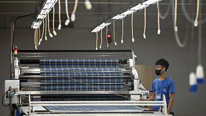 VietnamTrade_DB_07032025_A Trabalhador opera máquina automática de corte de tecido em fábrica de roupas na província de Thai Nguyen, Vietnã, em 2 de julho de 2025.