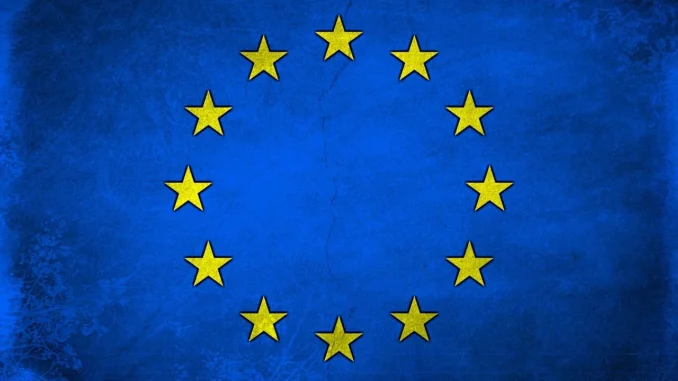 Bandeira da União Europeia azul com estrelas amarelas sobre um fundo claro, simbolizando unidade e cooperação europeia.