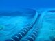 Cabo submarino de alta capacidade no fundo do mar, com linhas azuis e listras claras, transmitindo dados digitais para melhorar a conectividade na Ásia Oriental.