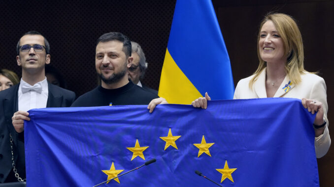 Presidente ucraniano Volodymyr Zelensky e líderes da União Europeia seguram a bandeira da UE durante visita ao Parlamento Europeu.