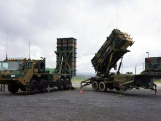 Lançadores de mísseis do sistema de defesa aérea Patriot em posição, com camuflagem militar e céu nublado ao fundo.